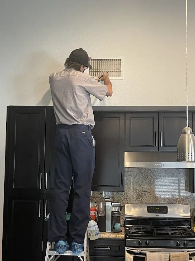 Technician inspecting an air vent during HVAC service in White Plains